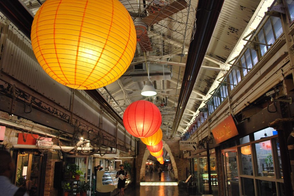 Lanteerns light up the chelsea market in New York City as customer buys food in background