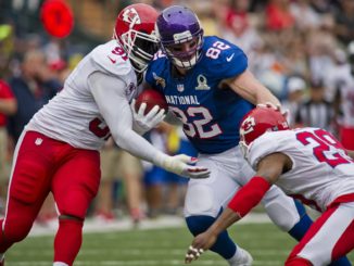 Two players take down their opponent from the opposite team in an NFL match