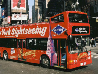 new york sightseeing bus drives past pedestrians in Times Square