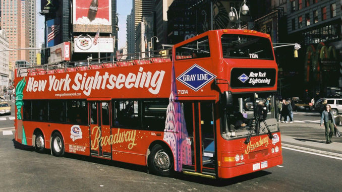 new york sightseeing bus drives past pedestrians in Times Square