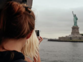 A view from the ferry of tourists taking pictures of the Statue of Liberty.