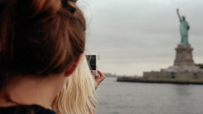 A view from the ferry of tourists taking pictures of the Statue of Liberty.