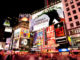 Night scene of Broadway at Times Square in Manhattan (New York City) with all the lit up billboards and advertisements, and many tourists people walking by.