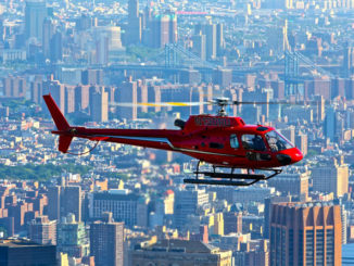 Red helicopter hovers high above NYC's buildings