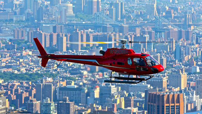 Red helicopter hovers high above NYC's buildings