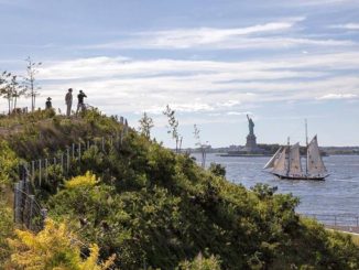 View of the Statue of Liberty from Governors Island as sail boat passes, in New York Harbour