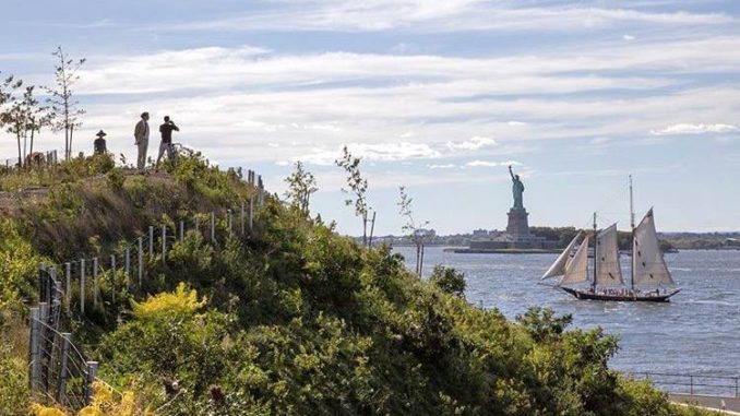 View of the Statue of Liberty from Governors Island as sail boat passes, in New York Harbour