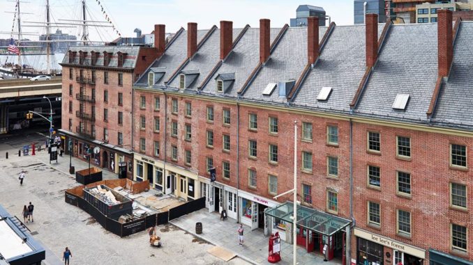 South Street Seaport Museum with ship in background and padestrians walking past shops undernearth