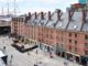 South Street Seaport Museum with ship in background and padestrians walking past shops undernearth