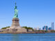 Tourists gather underneath the Statue of Liberty on a clear day