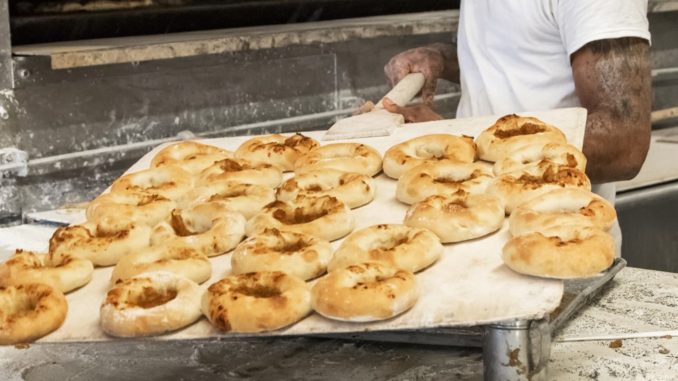 Freshly baked bagels taken from the oven by baker