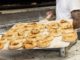 Freshly baked bagels taken from the oven by baker