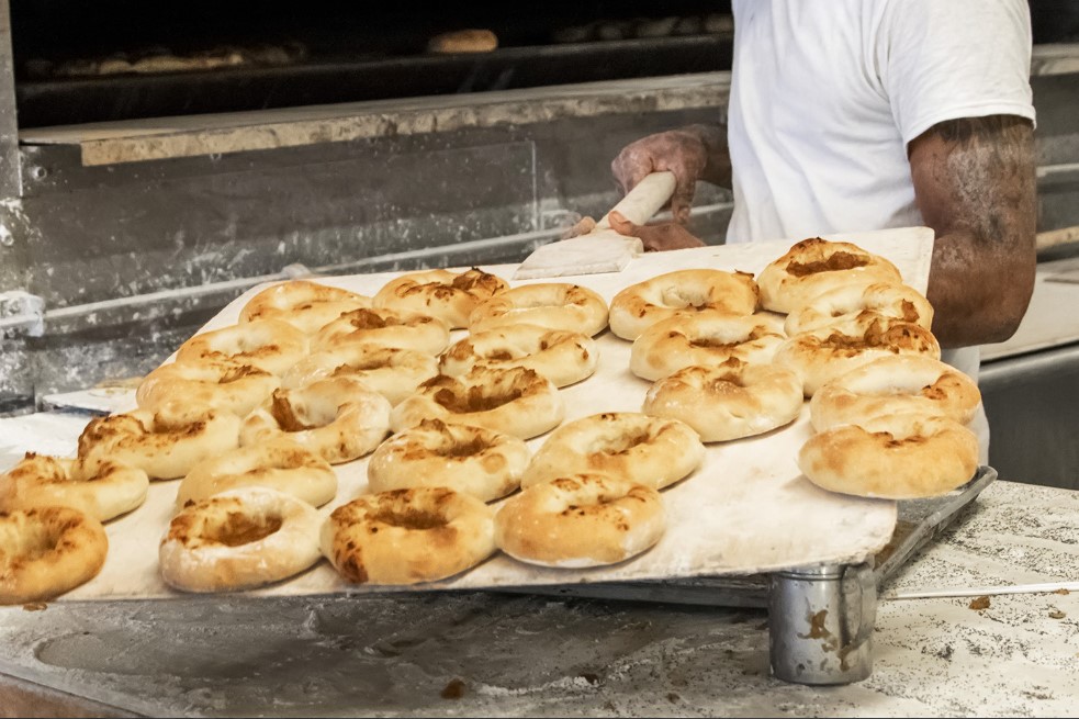 Freshly baked bagels taken from the oven by baker