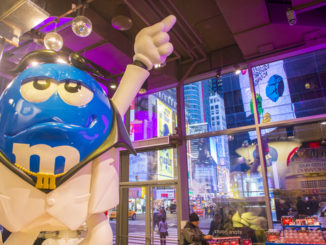 Inside M and M world new york as model points to ceiling
