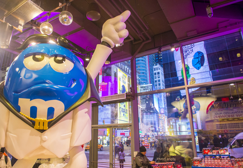 Inside M and M world new york as model points to ceiling