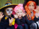 Portrait of three little girls in Halloween costumes looking at camera with frightening gesture