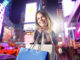 Woman with shopping bags with city shopping lights in the background
