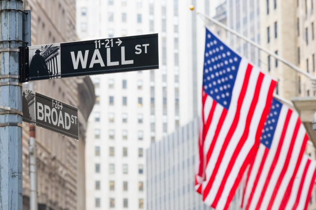 The famous wall street sign flanked by the flag of USA where to stay in new york