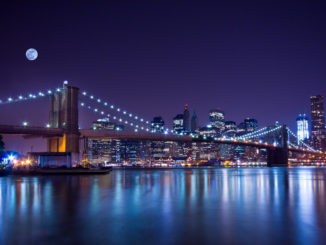 New York City's Brooklyn Bridge, at night, under a full moon