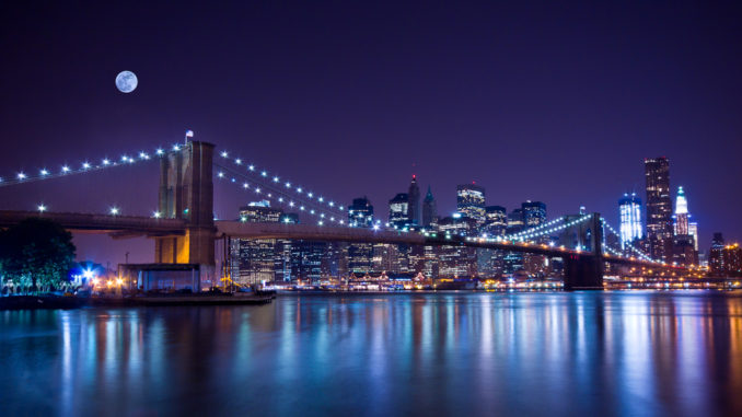 New York City's Brooklyn Bridge, at night, under a full moon