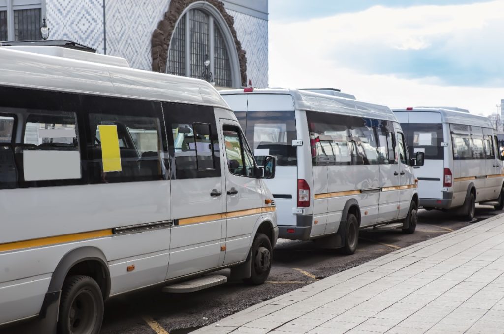 two white shuttle buses waiting to pick up passengers 