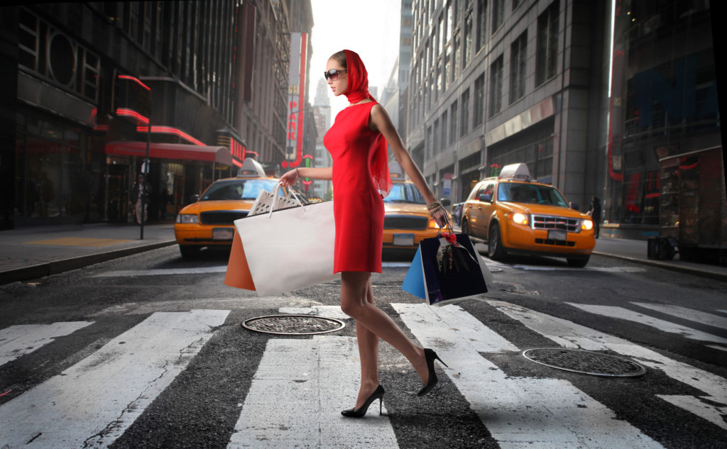 lady walking past yellow cabs with shopping bags - cheap shopping in new york