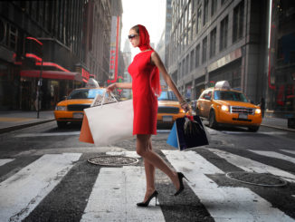 lady walking past yellow cabs with shopping bags - cheap shopping in new york