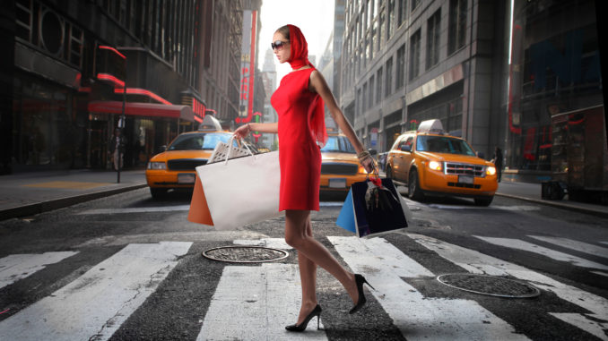 lady walking past yellow cabs with shopping bags - cheap shopping in new york