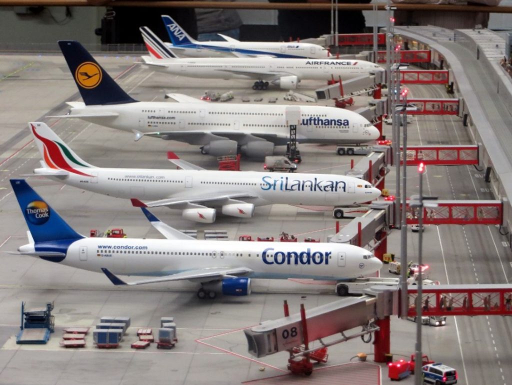 row of planes stands outside of airport