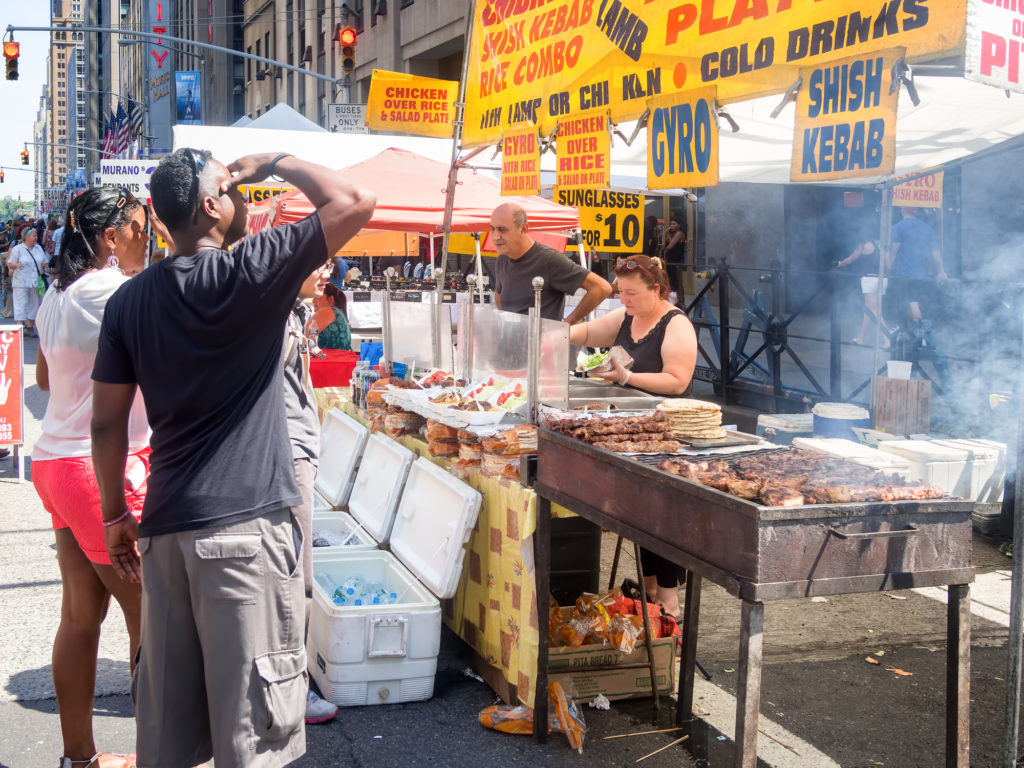 Street kiosk selling ethnic food at a street fair next to the Rockefeller Center in Manhattan - unique things to do in NYC