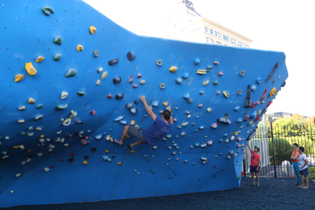 Rock climbing enthusiast scales the wall at Dumbo Boulders - unique things to do in NYC
