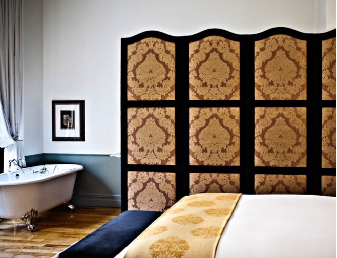 A bedroom in the NoMad Hotel features bed and a freestanding bathtub with a divider for privacy