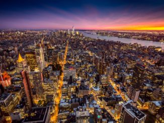 rial shot of Manhattan illuminated by the night time lights