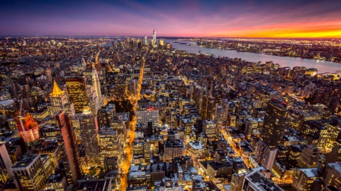 rial shot of Manhattan illuminated by the night time lights