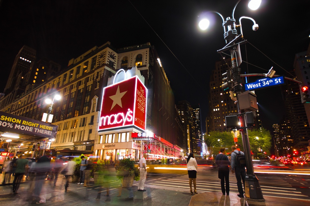 People walk past Macy's department store at night