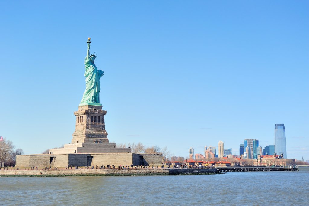 Large crowd gathers underneath the Statue of Liberty