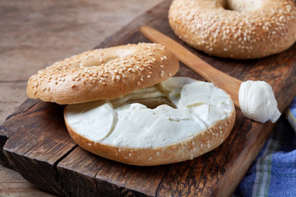 generous helping of cream cheese on a sesame bagel - things to eat in new york