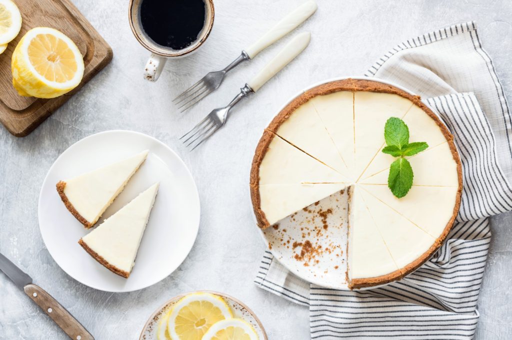 cake sits on a plate with cup of coffee and a lemon also on table- things to eat in new york