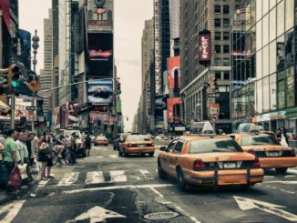 busy street in new york where people wait for traffic in front of yellow cabs - things to eat in new york