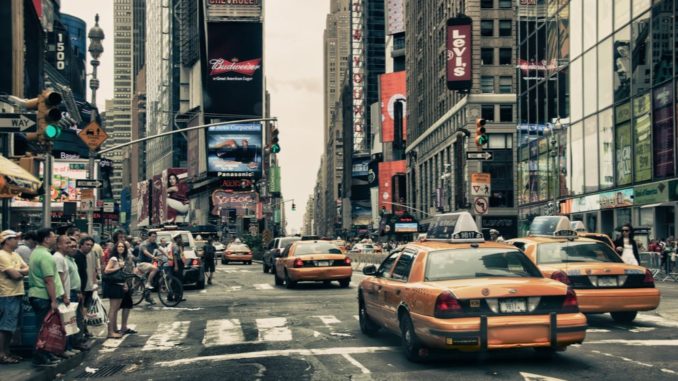 busy street in new york where people wait for traffic in front of yellow cabs - things to eat in new york