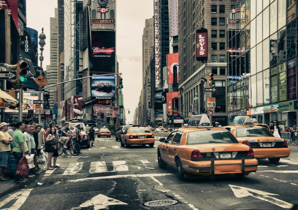 busy street in new york where people wait for traffic in front of yellow cabs - things to eat in new york