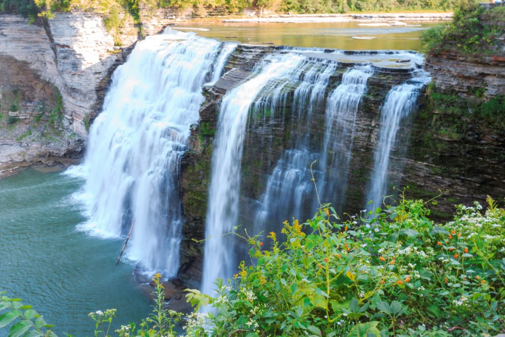 water comes over the rocks in a waterfall at letchworth, one of the best national parks in new york