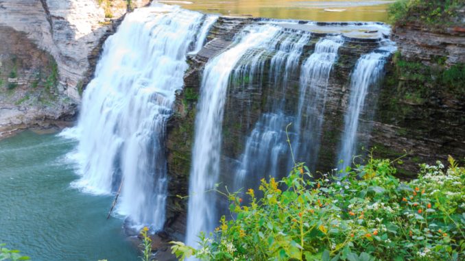 water comes over the rocks in a waterfall at letchworth, one of the best national parks in new york